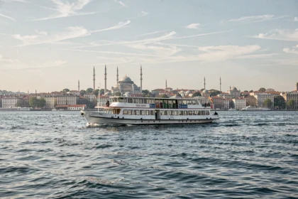 Ferry touristique blanc naviguant sur le Bosphore avec la skyline historique d'Istanbul en arrière-plan