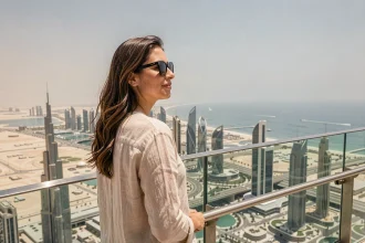 Femme sur la terrasse extérieure du Burj Khalifa avec vue panoramique sur le skyline de Dubaï