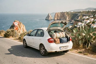 Voiture de location garée sur une route côtière sinueuse en Sicile avec mer turquoise en arrière-plan